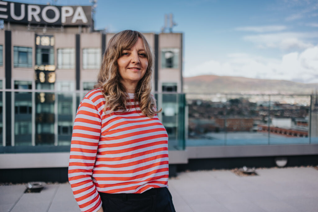 Image of Lisa standing on a roof top in a red stripped shirt